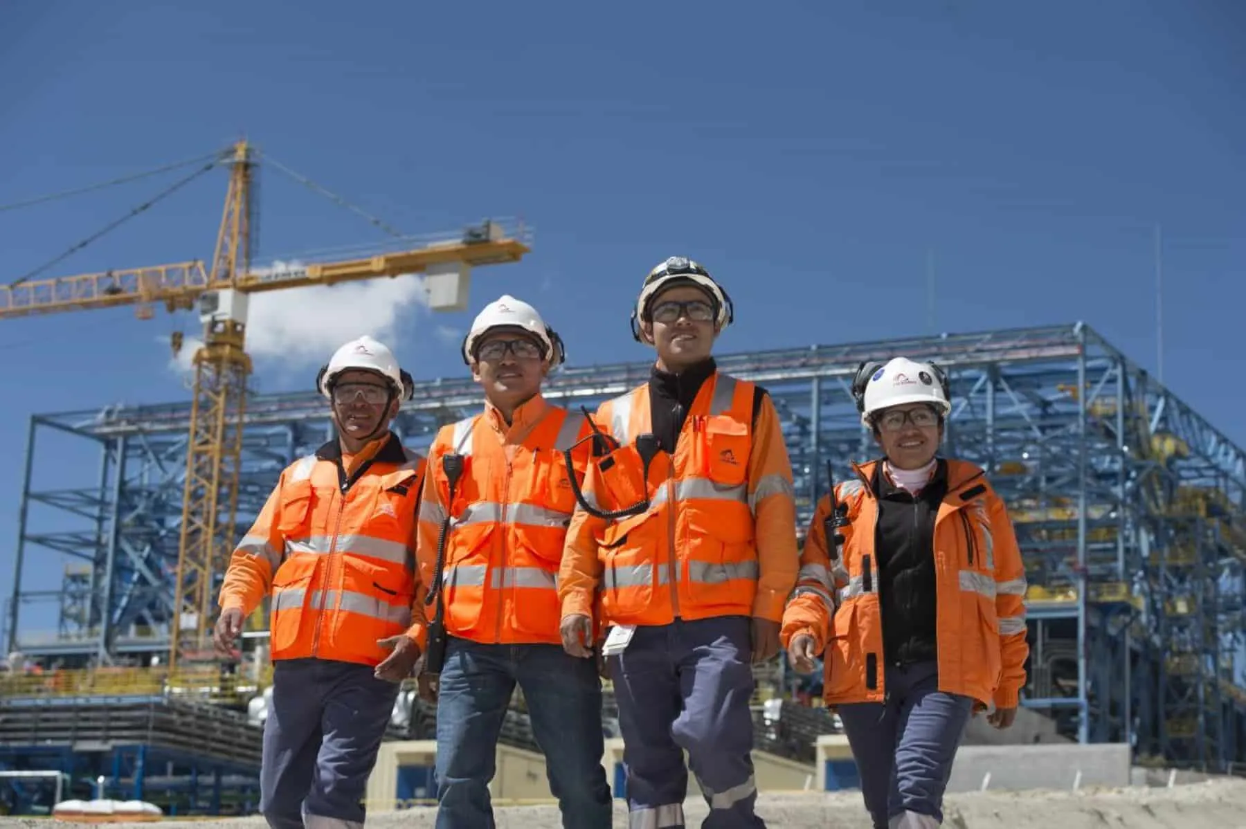 Cuatro trabajadores con casco y chaleco reflectante en una obra
