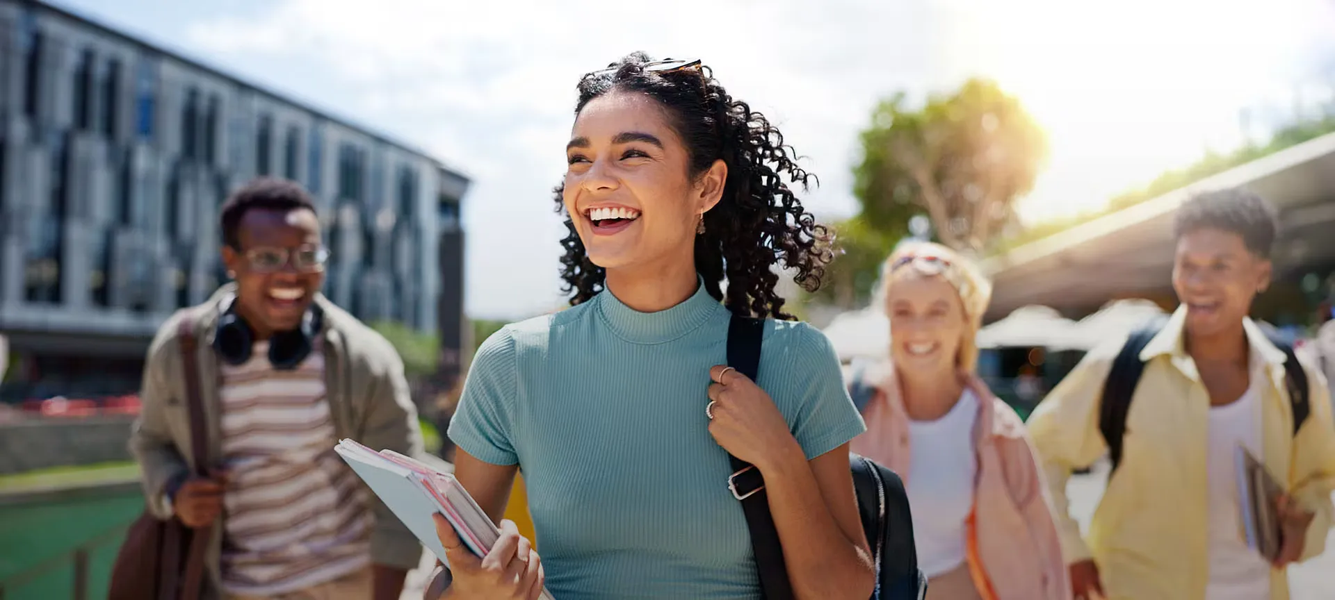 Grupo de estudiantes caminando y sonriendo por un campus